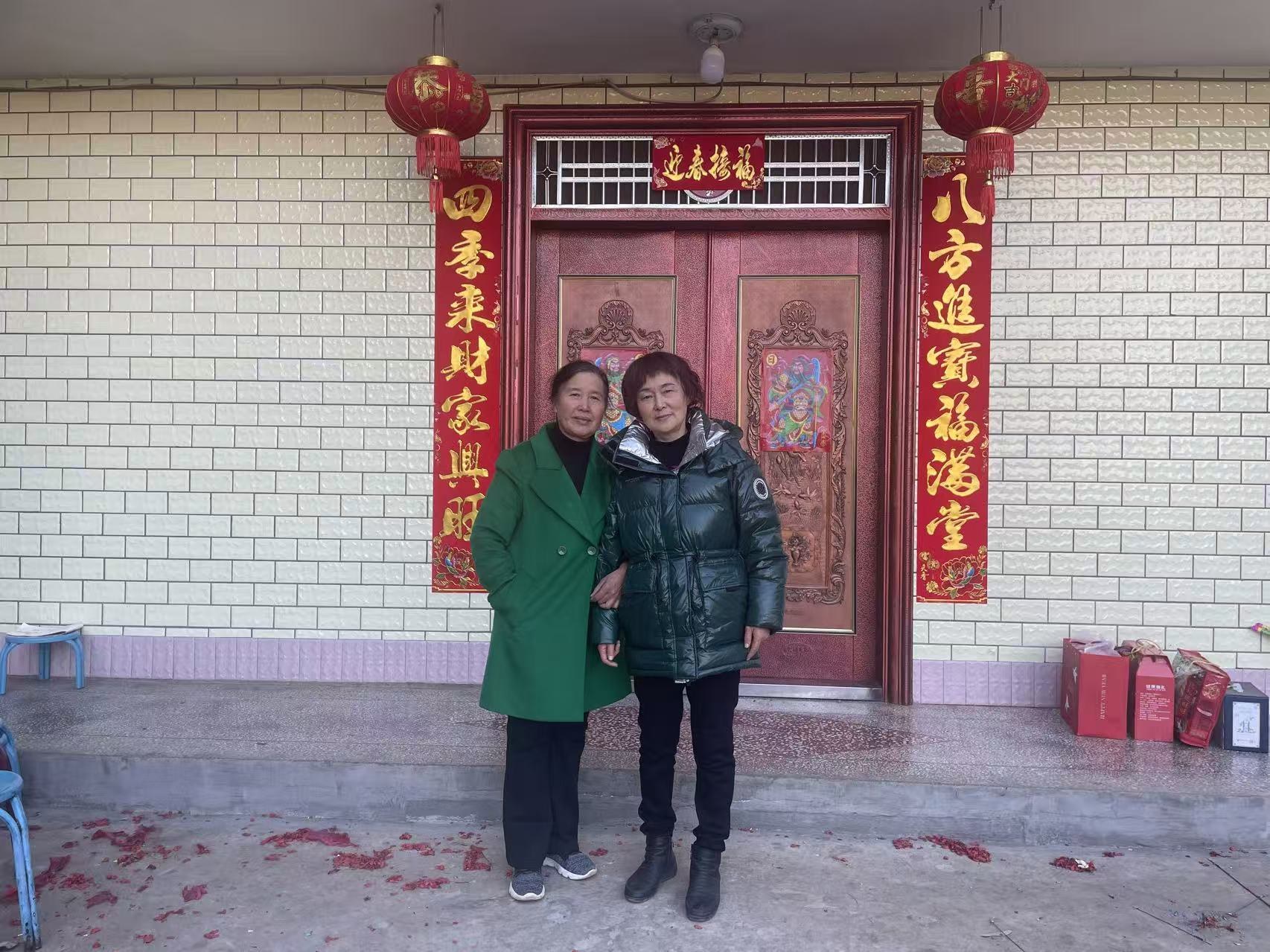 Two older women standing in front of a home